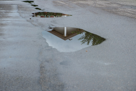 Reflection of a house in a water puddle after a rain stormの写真素材