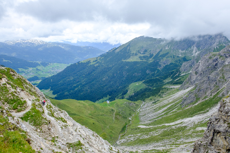 Two hikers descending into a valley in the Allgaeu moutains on a cloudy day, Austriaの写真素材
