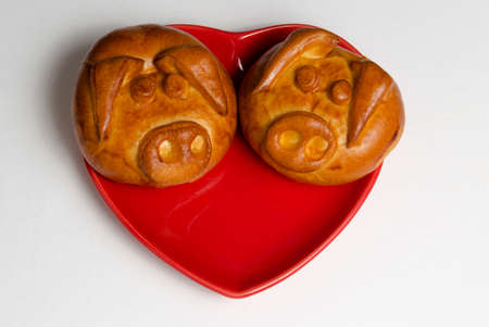Two pigs of bread in a red heart-shaped plateの写真素材