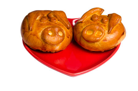 Two pigs of bread in a red heart-shaped plate isolateの写真素材