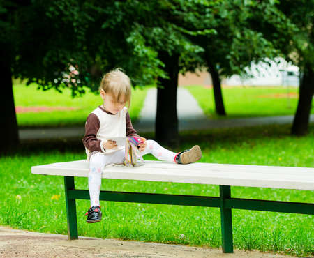 Girl sitting on a bench in the park in summerの写真素材