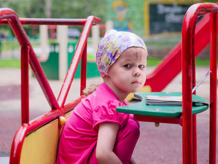 Little girl on a Carnival Carousel at an amusement park or theme park. Warm afternoon sun in the backgroundの写真素材