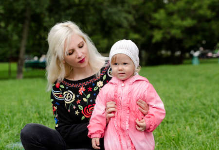 Young mother is holding a little girl for a walk in the parkの写真素材