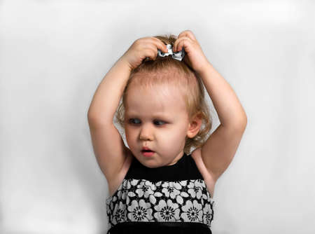 Little girl in a black and white dress touching bow on her head and is surprisedの写真素材