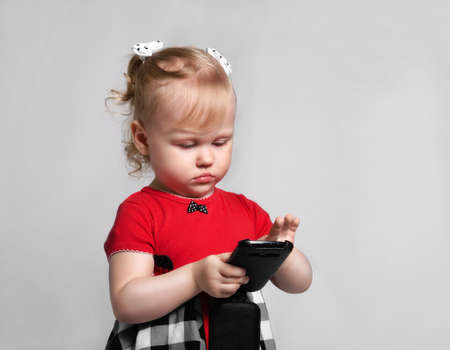 little girl with smartphone look screet photo studioの写真素材