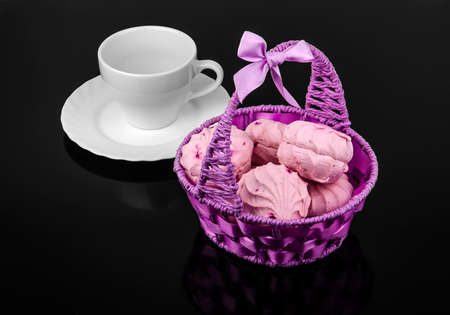 Berry purple marshmallow in the basket with a cup and saucer on a black mirror tableの写真素材