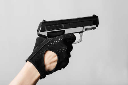 Female hand with a pistol in a black glove aim and pulled the triggerの写真素材