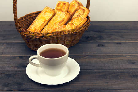 Basket with bread sticks, white porcelain cup and saucer standing on a wooden table background - small DoF focus put only to pierの写真素材