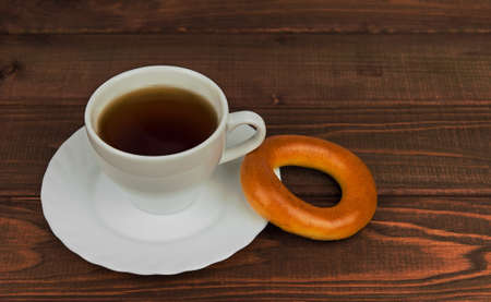 On a wooden table cup of tea and fresh-faced bagel biscuit - small DoF focus put only to pierの写真素材