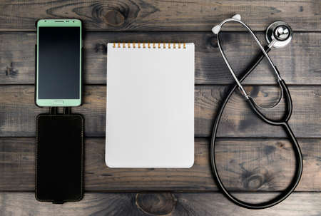 On the wooden table is a smartphone and pen green color with white display, there are a place in your text or pictureの写真素材