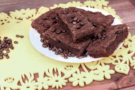 On a wooden table on yellow  plate of chocolate truffle cake, a lot of coffee beansの写真素材