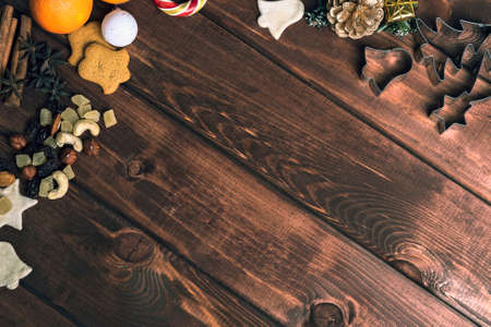 On a wooden desk background Christmas composition - candy cane, dough figurines, Christmas-tree branch Christmas balls, raisins, nuts, cinnamon sticks, cookies, star anise, mandarins bumpの写真素材
