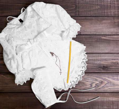 On a wooden background table set for the Christening baby - shirt, cap, towel, diaper, candle, gold cross on a chainの写真素材