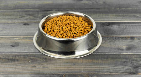 Dry Dog Food in a Stainless Steel Bowl on Hardword Floorの写真素材