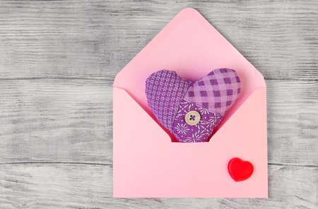 On a white wooden table composition for Valentine's Day, heart tissue in an envelope, a letter, a...