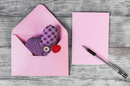 On a white wooden table composition for Valentine's Day, heart tissue in an envelope, a letter, a...