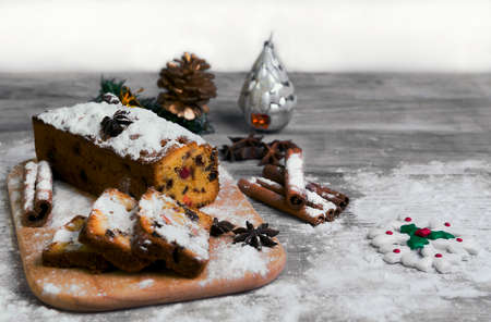 On a wooden desk background Christmas stollen Stollen, a Christmas tree branch, pine cone, gift,...