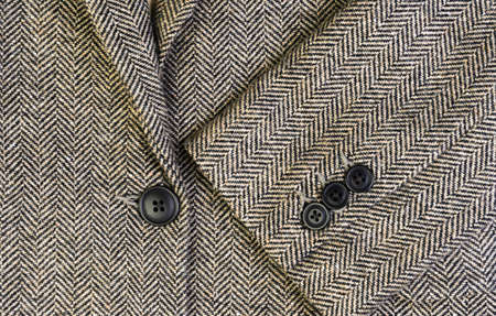 Herringbone tweed women jacket with closeup on wool fabric texture with buttons