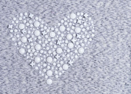 The texture of gray and white knitted heart of rhinestones and beads