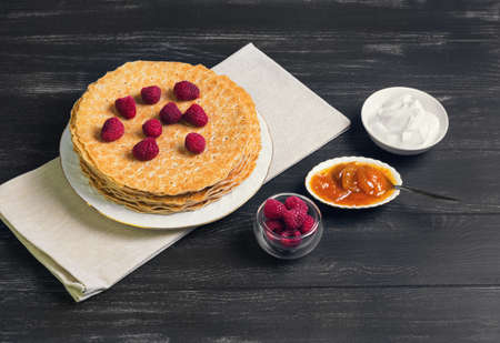A stack of pancakes on a white porcelain plate, raspberry, apricot jam, sour creamの写真素材