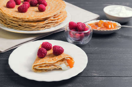 A stack of pancakes on a white porcelain plate, raspberry, apricot jam, sour creamの写真素材