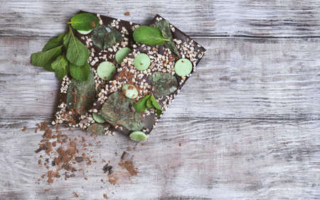 Chocolate, hand-made with mint leaves, candied violets, lemon candy, nuts, chips, cocoa powder on a light wooden background in rustic style, top view, clean empty place for textの写真素材