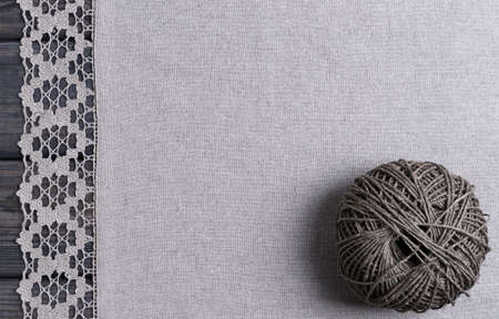 On a gray wooden background light gray fabric from flax coarse burlap candle with white lace...