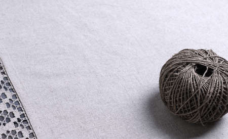 On a gray wooden background light gray fabric from flax coarse burlap candle with white lace...