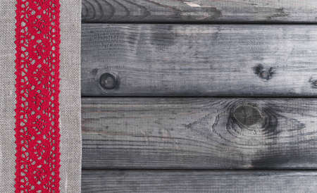 Light gray fabric from flax coarse burlap candle with red lace handmade on gray wooden backgroundの写真素材