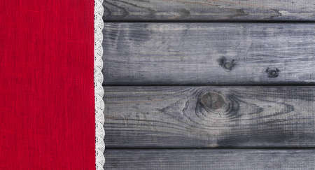 On a gray background of wooden red cloth with white linen woven handmade laceの写真素材