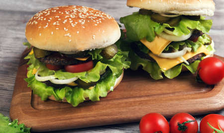 Two big cheeseburger deluxe high on light wooden background in rustic styleの写真素材