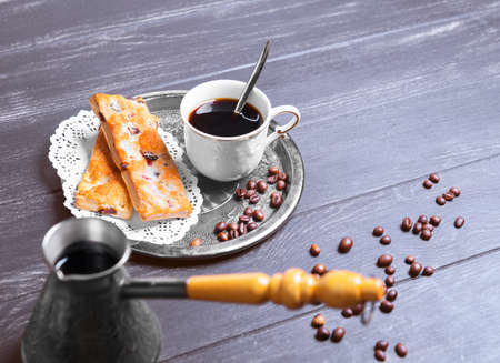 Brewing coffee and two pieces of biscuits, beans scattered on a dark black wooden background in rustic style, Empty place for textの写真素材