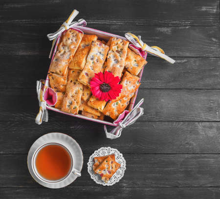 Breakfast Hot Tea in a white porcelain dish, tissue basket with freshly baked cookies on a dark...