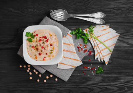 Delicious healthy snack healthy vegan cauliflower hummus and homemade tortilla on white plate on a dark brown wooden background, top viewの写真素材