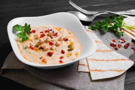 Delicious healthy snack healthy vegan cauliflower hummus and homemade tortilla on white plate on a dark brown wooden background, top viewの写真素材