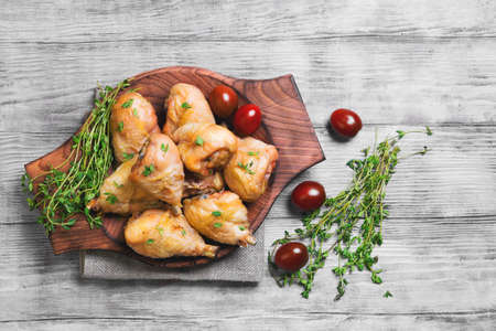 Chicken poultry meat - legs drumstick chicken with thyme seasoning, fresh thyme on sackcloth, cherry tomatoes on a light shabby white wooden background, top viewの写真素材