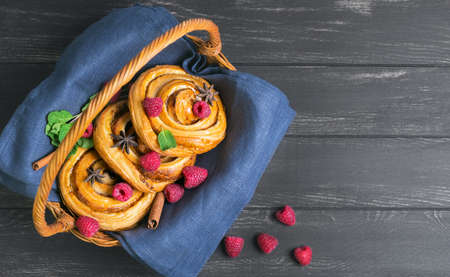 Several Denish buns brioche with raspberry, cinnamon, star anise, mint on a basket with a cloth on a...