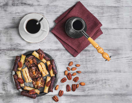 Baklava walnut, chocolate, almonds, pecans on a round metal tray on a light wooden background, top viewの写真素材