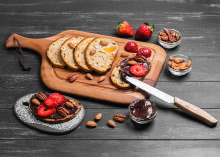 sandwiches crostini with chocolate paste, a large red strawberry, pecans, hazelnuts, almonds and...
