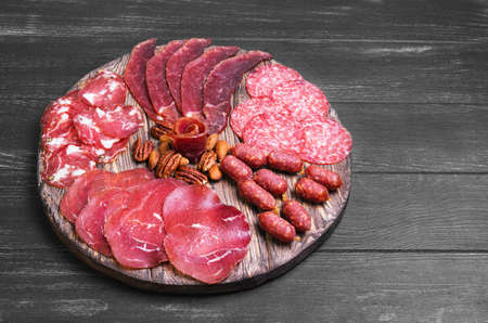 Meat-cutting sausage jerked, prosciutto, smoked sturgeon, nuts, almonds, pecans, on the round board...