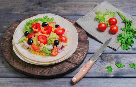 Delicious grilled chicken, fresh vegetables, homemade tortillas, vegetables for stuffing tortillas, rustic cutting board on gray wooden backgroundの写真素材
