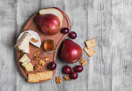 Fruit pear whole, grapes, pear cut in half, cheese, camembert cheese, goat cheese, honey, walnuts on...