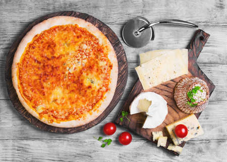 4 Pizza four cheese, goat cheese, lettuce, cherry tomatoes and a knife on a light wooden background, top viewの写真素材