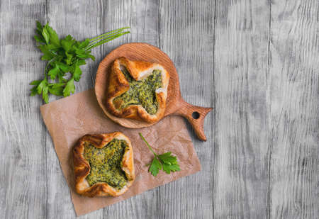 Italian puff pastry patties fagottini stuffed with cheese and spinach, parsley on a light background white wooden, top viewの写真素材