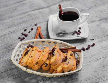 Italian biscotti cookies in a basket and morning coffee in a white cup, coffee beans on a light white wooden backgroundの写真素材