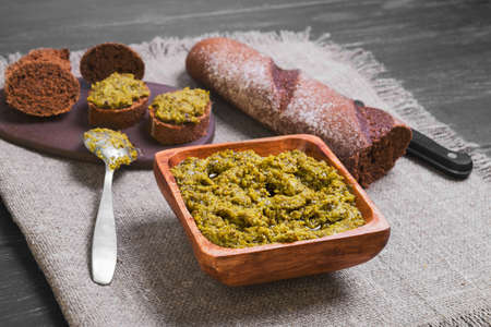 Italian pesto sauce, bagget, small sandwiches bruschetta, black wooden background surfaceの写真素材
