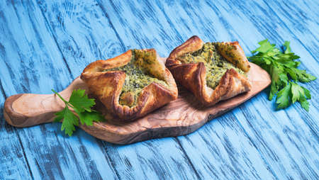 Italian puff pastry patties fagottini stuffed with cheese and spinach, parsley on blue background woodenの写真素材