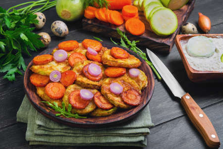 Vegetables ingredients for fried vegetable dishes in dough. Vegetables marrows white squashes, carrots, parsley, lettuce, dill, tomato, onions, quail eggs, flour Black wood backgroundの写真素材
