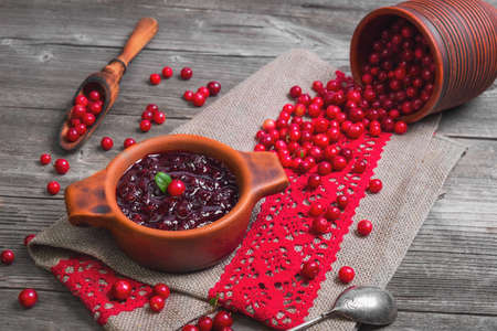 Homemade Lingonberry cranberry cowberries sauce. Fresh berries Lingonberry cranberries cowberries in ceramic cup. Lingonberry on table. Grey rustic wooden background.の写真素材