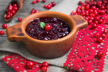 Homemade Lingonberry cranberry cowberries sauce. Fresh berries Lingonberry cranberries cowberries in ceramic cup. Lingonberry on table. Grey rustic wooden background.の写真素材